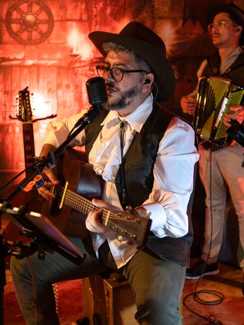 Vocalista dos Folkadelicos com violão sob luz vermelha