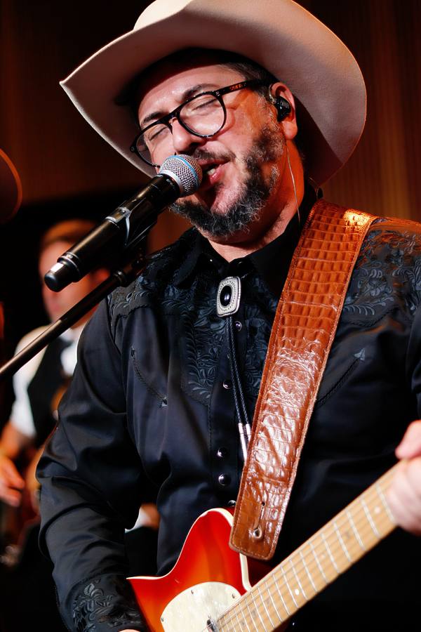 Vocalista de chapéu cantando e tocando guitarra no evento da RAM