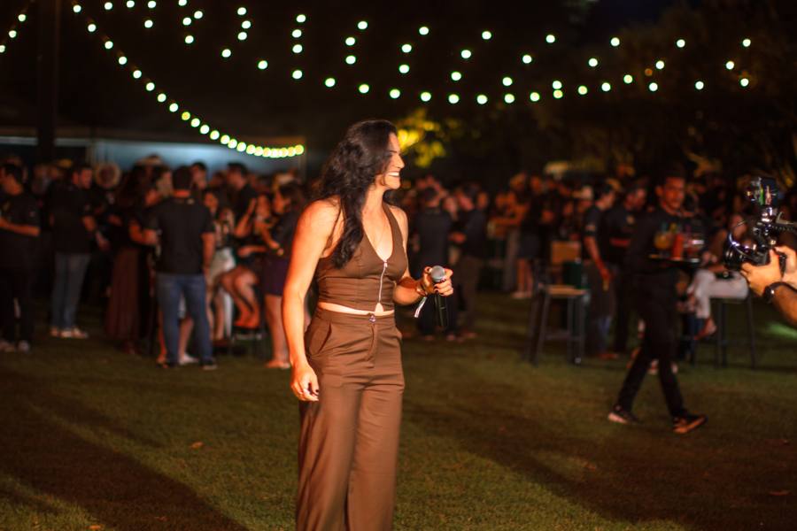 Cantora no gramado diante do público sob varal de luzes no Paiol