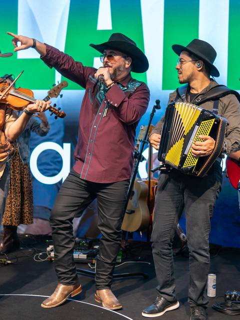 Folkadelicos com violino, sanfona e guitarra num palco corporativo
