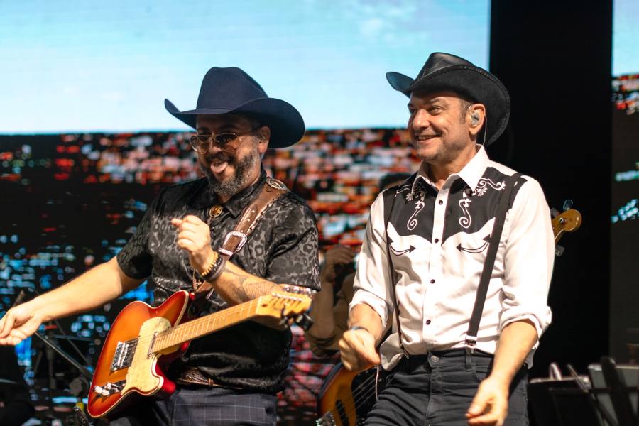 Dois guitarristas de chapéu dançando no palco do Campo Real