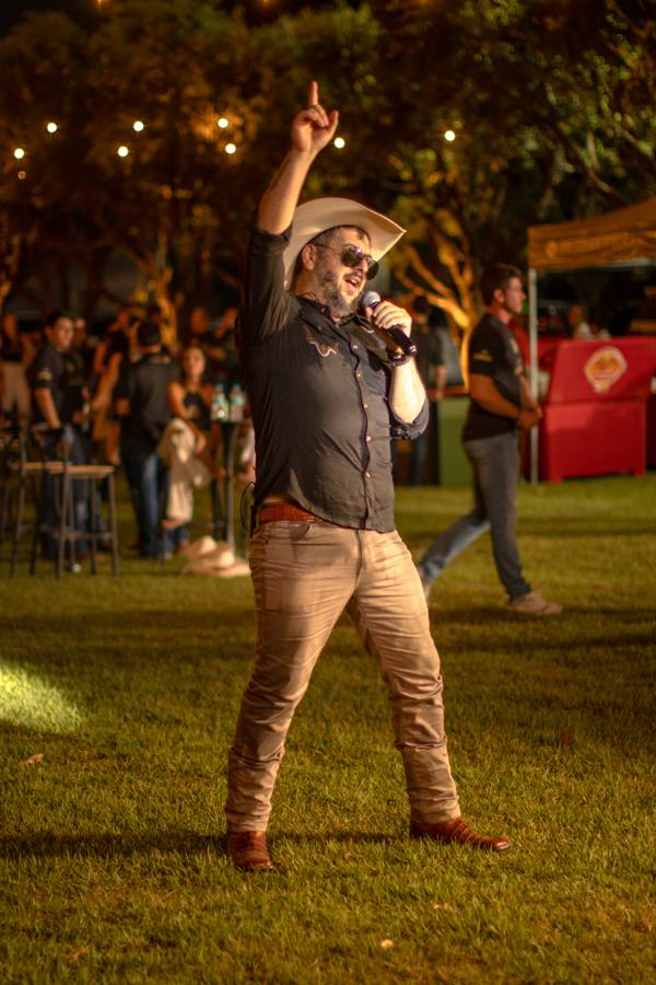 Vocalista cantando no gramado em meio ao público no Paiol