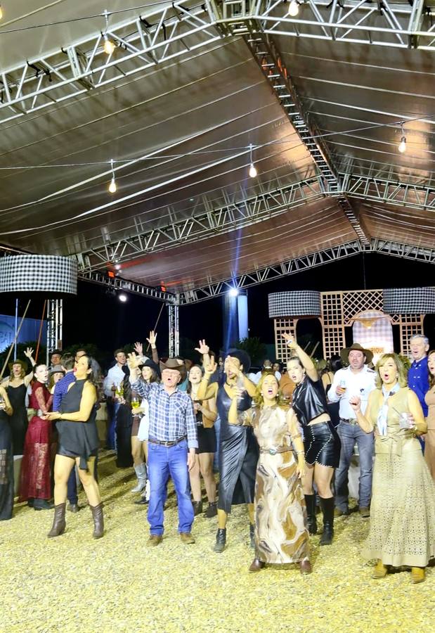 Convidados de chapéu dançando sob a tenda do Campo Real